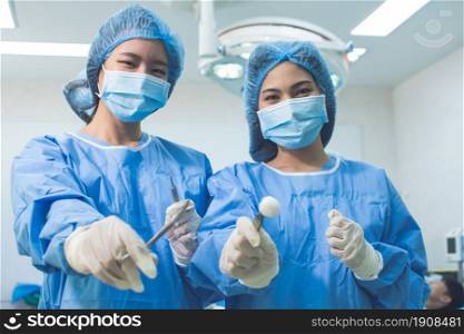 Portrait of two asian female doctors with blur background of medical team doing surgical operation at hospital