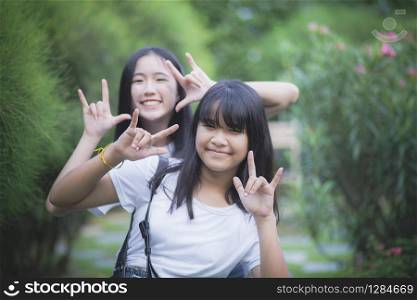 portrait of two asian teenager relaxing with happiness in green park