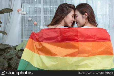 Portrait of two asian women with rainbow flag and standing in a house showing LBGT concept.
