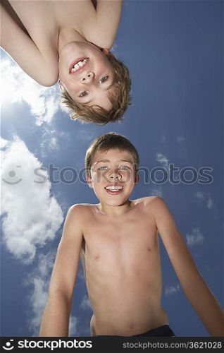 Portrait of two boys (6-11) bending down, view from below