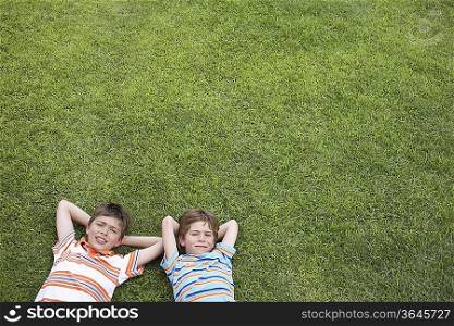 Portrait of two boys (6-11) lying on grass, hands behind head