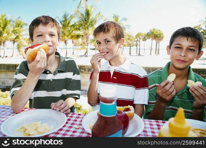 Portrait of two boys and a teenage boy eating food