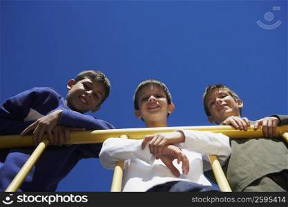 Portrait of two boys and a teenage boy leaning against a railing and smiling