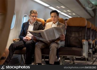 Portrait of two business men reading newspaper in plane enjoying long business flight. Man in brown suit in airplane cabin holding newspaper.