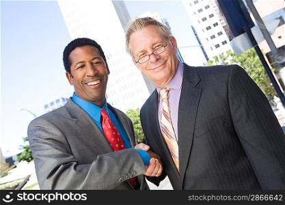 Portrait of two businessmen shaking hands, outdoors