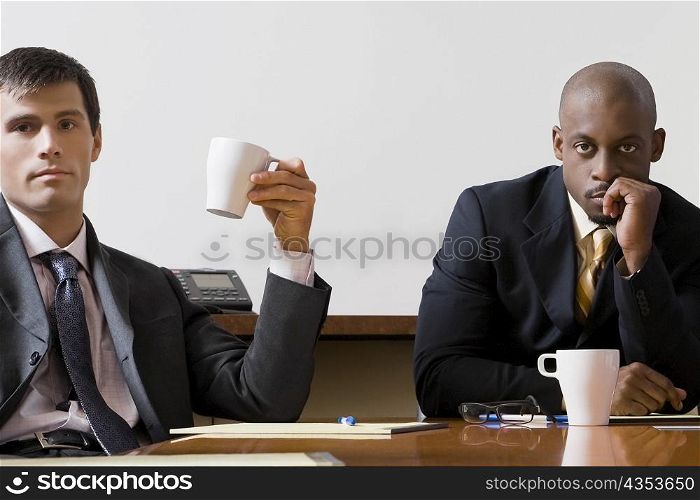 Portrait of two businessmen sitting in a board room