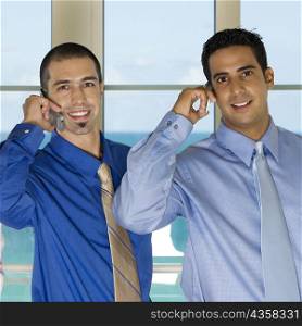 Portrait of two businessmen using mobile phones