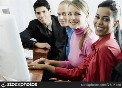 Portrait of two businesswomen and two businessmen sitting in front of a computer