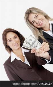 Portrait of two businesswomen holding American paper currency