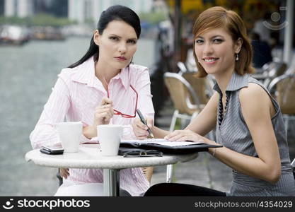 Portrait of two businesswomen sitting at a sidewalk cafe