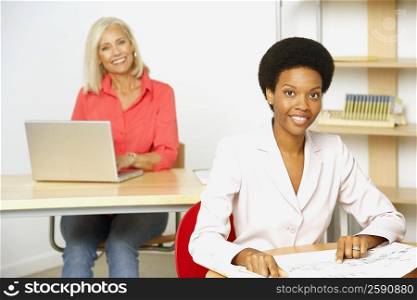 Portrait of two businesswomen sitting in an office and smiling