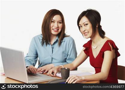 Portrait of two businesswomen sitting in front of a laptop