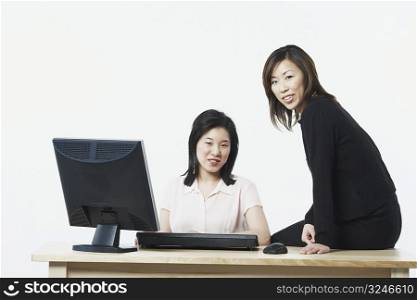 Portrait of two businesswomen smiling in front of a computer