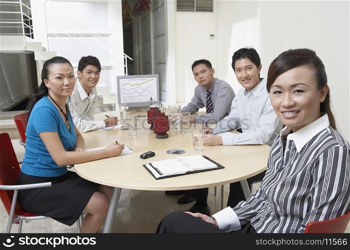 Portrait of two businesswomen with three businessmen sitting at a conference table
