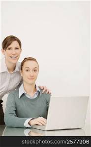 Portrait of two businesswomen working on a laptop and smiling