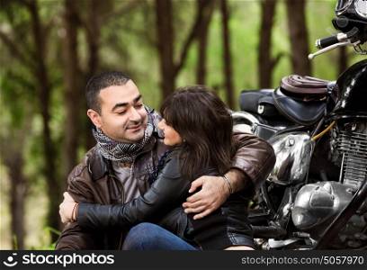 Portrait of two calm people sitting near motorcycle, looking on each other and resting outdoors, romantic relationship, happy adventure, relaxation after extreme trip