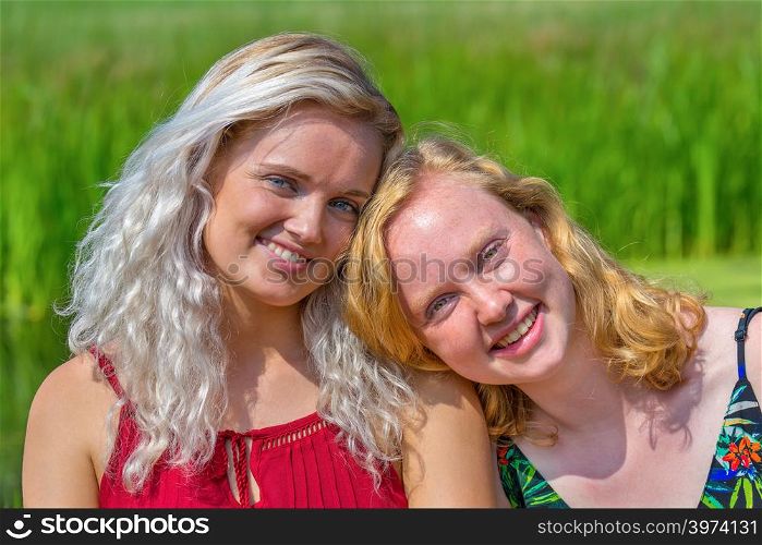 Portrait of two close young dutch sisters in green nature