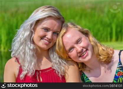Portrait of two close young dutch sisters in green nature