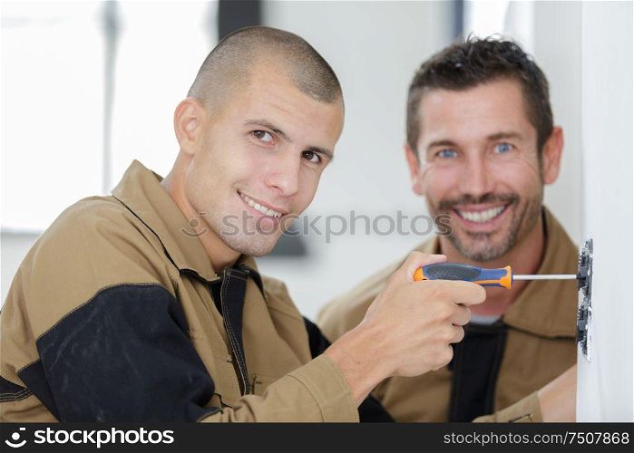 portrait of two contractors working indoors one using screwdriver