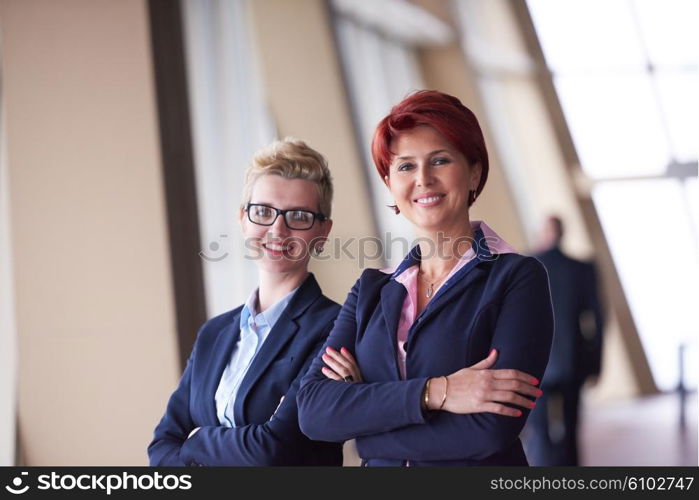 portrait of two corporate business woman at modern bright office interior standing in group as team