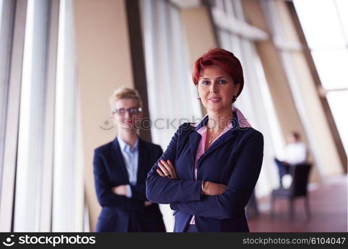 portrait of two corporate business woman at modern bright office interior standing in group as team