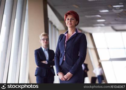 portrait of two corporate business woman at modern bright office interior standing in group as team