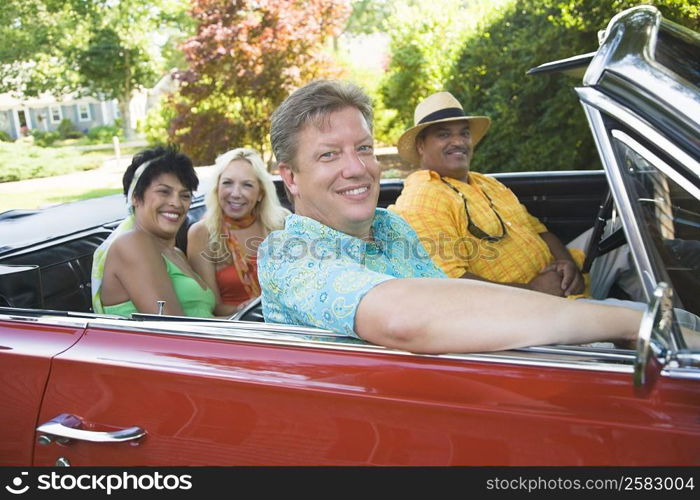 Portrait of two couples sitting on a convertible car