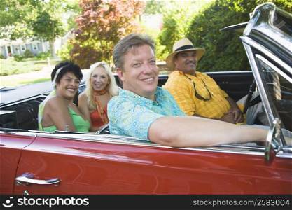 Portrait of two couples sitting on a convertible car