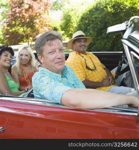 Portrait of two couples sitting on a convertible car