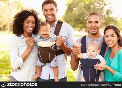 Portrait Of Two Families With Baby Carriers In Park