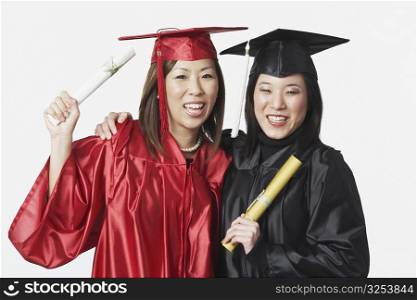 Portrait of two female graduates holding diplomas