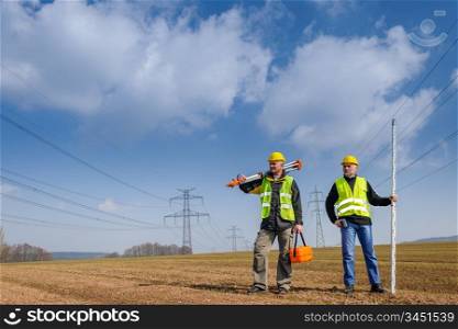 Portrait of two geodesist holding measuring equipment on construction site