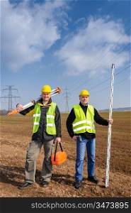 Portrait of two geodesist holding measuring equipment on construction site