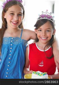 Portrait of two girls (7-9 10-12) in tiaras smiling