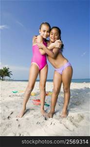 Portrait of two girls hugging each other on the beach