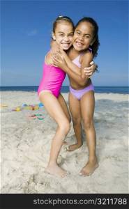 Portrait of two girls hugging each other on the beach