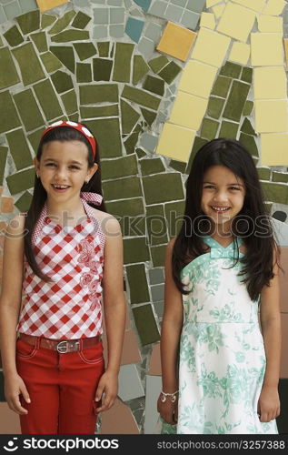 Portrait of two girls standing in front of a colorful wall