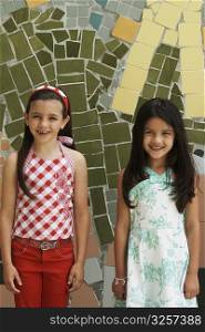 Portrait of two girls standing in front of a colorful wall