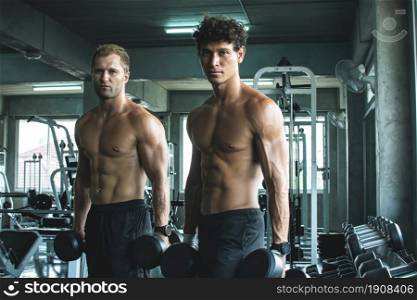 Portrait of two handsome muscular men are lifting dumbbells in fitness or gym. Healthy and Lifestyle Concept.