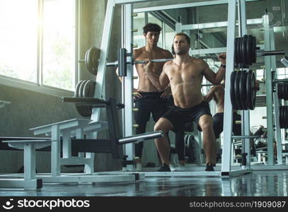 Portrait of two handsome muscular men are lifting weight in fitness or gym. Healthy and Lifestyle Concept.