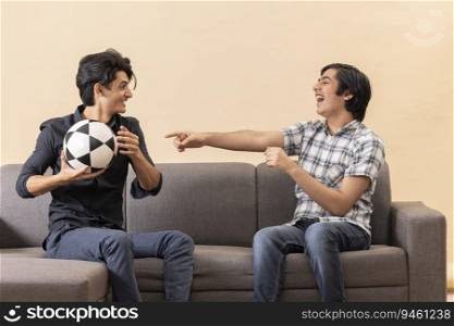Portrait of two happy teenage boys playing football indoors 