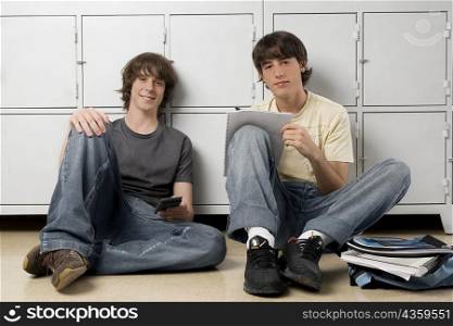 Portrait of two high school students sitting in front of lockers