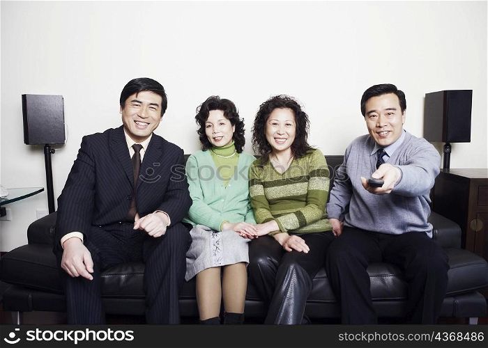 Portrait of two mature couples sitting together on a couch smiling