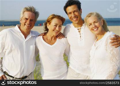 Portrait of two mature couples standing with their arms around each other on the beach