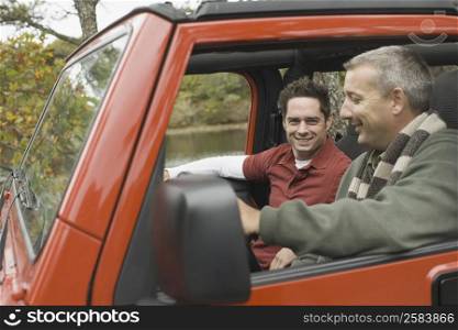 Portrait of two mature men sitting in a jeep