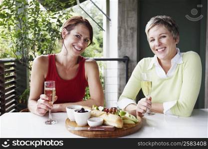 Portrait of two mature women holding champagne flutes and smiling