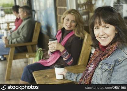 Portrait of two mature women holding disposable cups and smiling