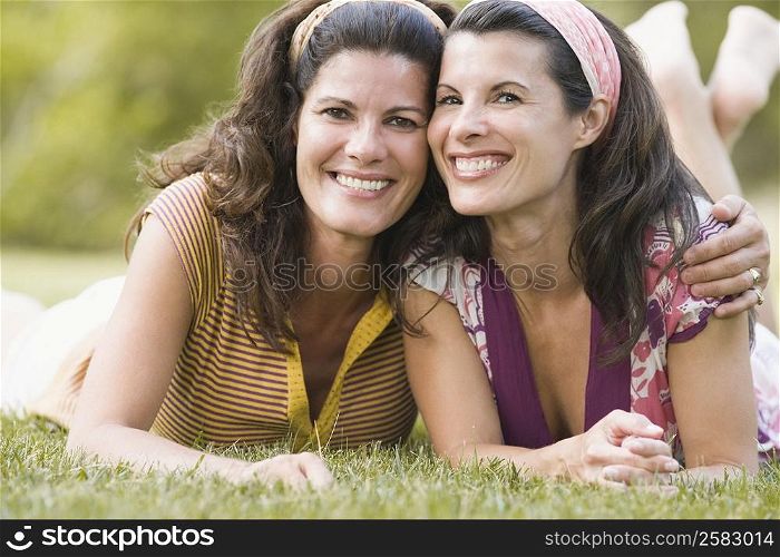 Portrait of two mature women lying on grass and smiling