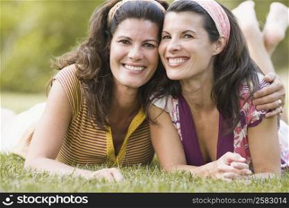Portrait of two mature women lying on grass and smiling