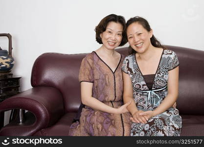 Portrait of two mature women sitting on a couch and smiling